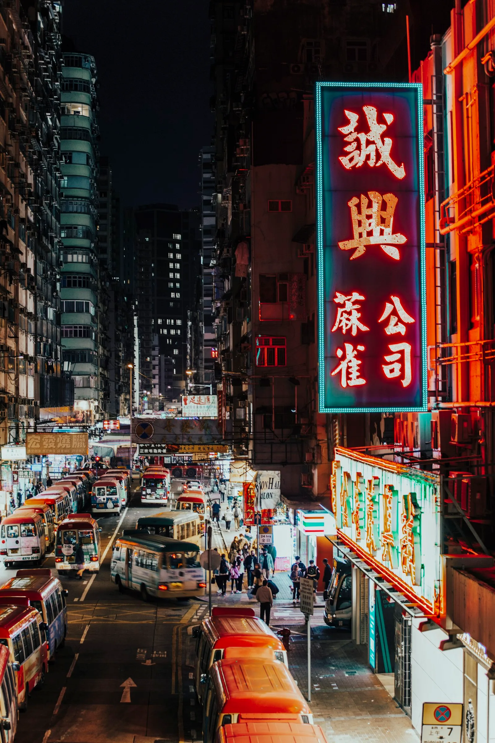 A neon-lit street full of traffic at night