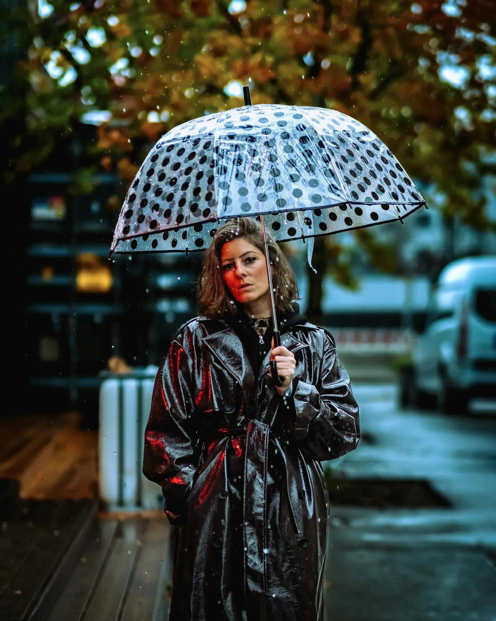 A woman with a clear polka-dot umbrella in the rain